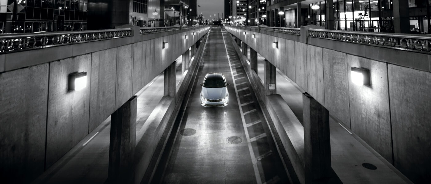 A black and white picture of a Kia Optima driving on a ramp