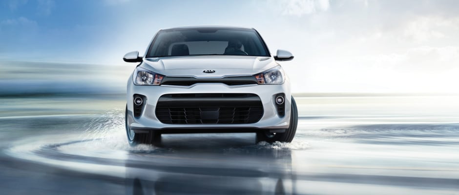 Test Drive a Kia Rio today A Kida Rio driving on wet pavement