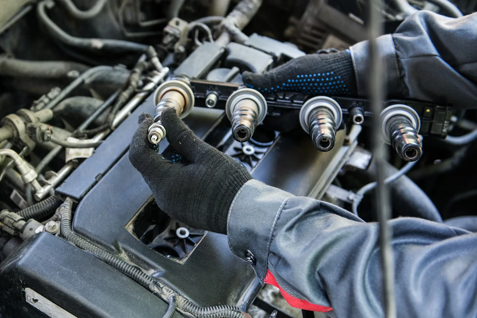 Technician removing ignition coils and spark plugs from an engine
