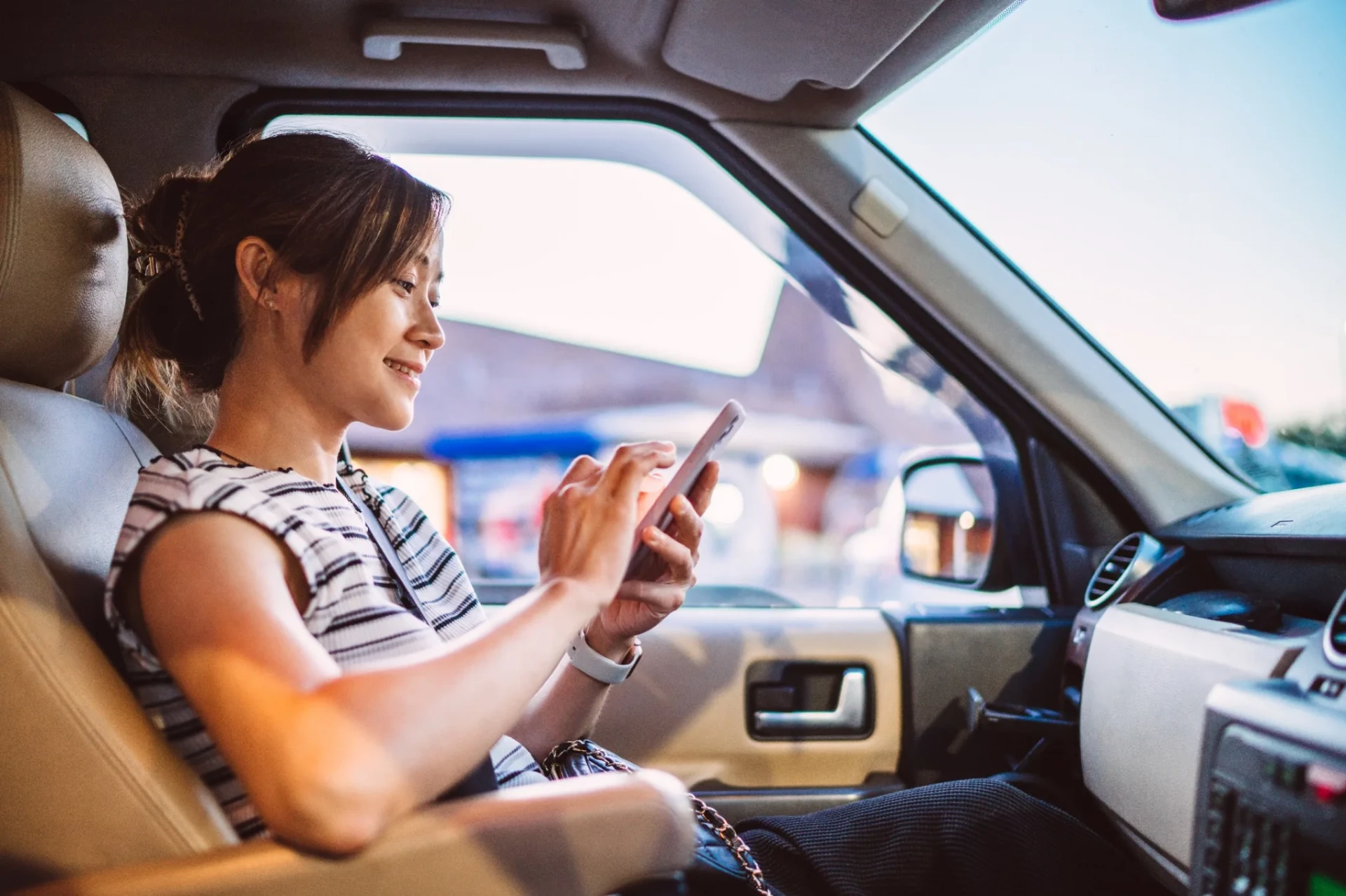 Driver in Palm Beach checking her connected-car mobile app — real-time location, geofencing and valet mode from the LoJack companion app.