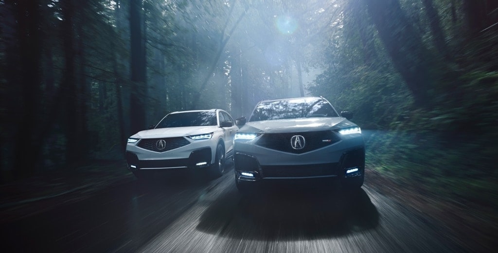 Two 2026 Acura MDX models being driven through a forested road