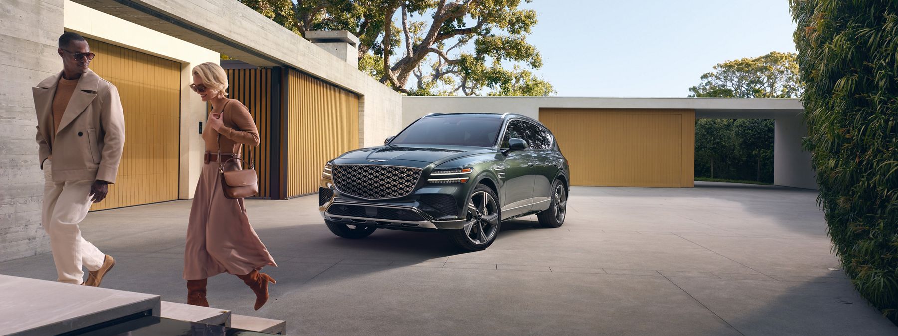 A couple walking in front of the 2026 Genesis GV80