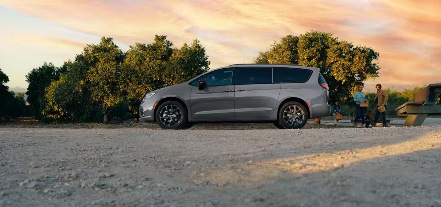 grey 2024 chrysler pacifica parked in gravel lot while family unloads trunk