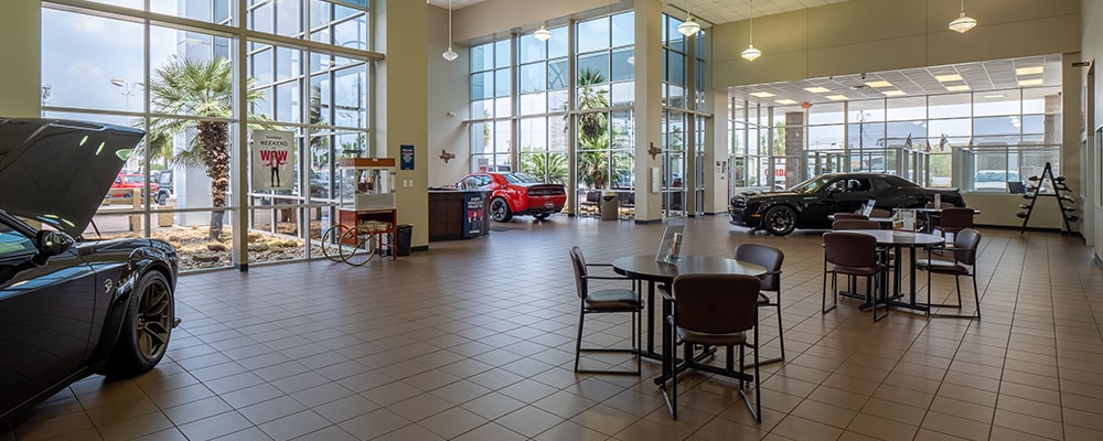 Find out about buying, servicing, and financing Dodge, Chrysler, Jeep, Ram vehicles at Autonation Chrysler Dodge Jeep Ram Houston Lobby of Autonation Chrysler Dodge Jeep Ram Houston, featuring large windows and 2 round tables with chairs