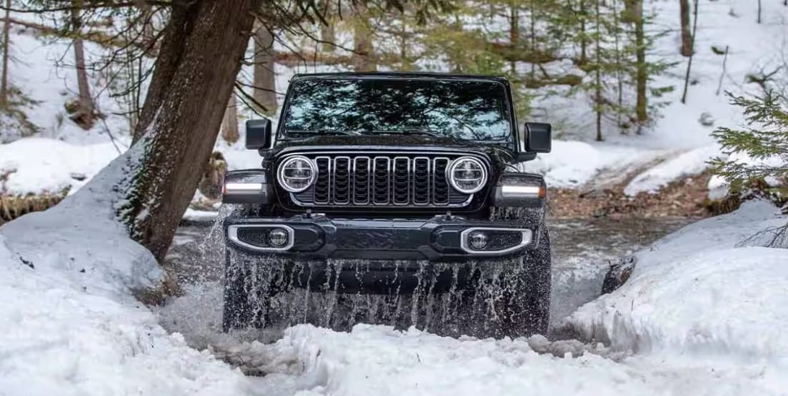 2026 Jeep® Wrangler driving through snowy creek