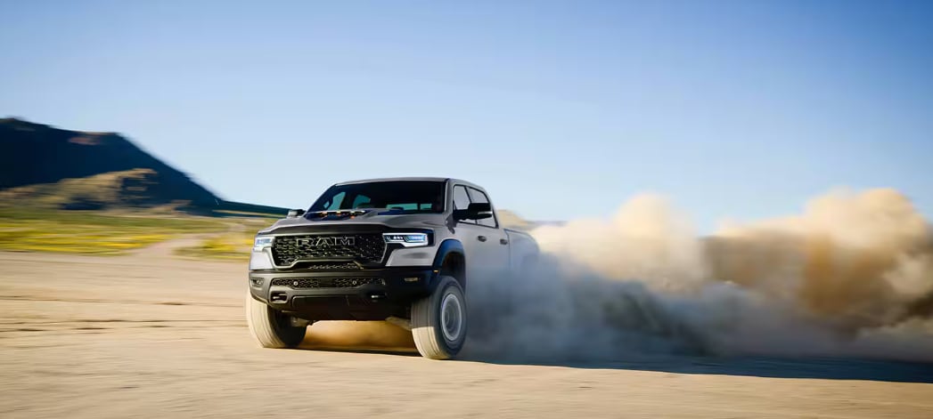 RAM 1500 RHO kicking up dust while off-roading in the desert.