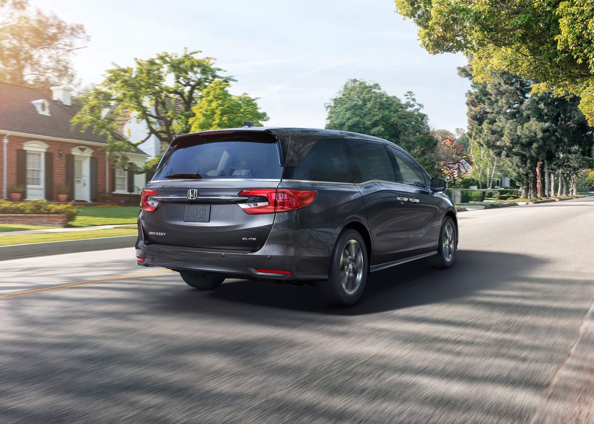 Silver Honda Odyssey driving down a neighborhood street.jpeg