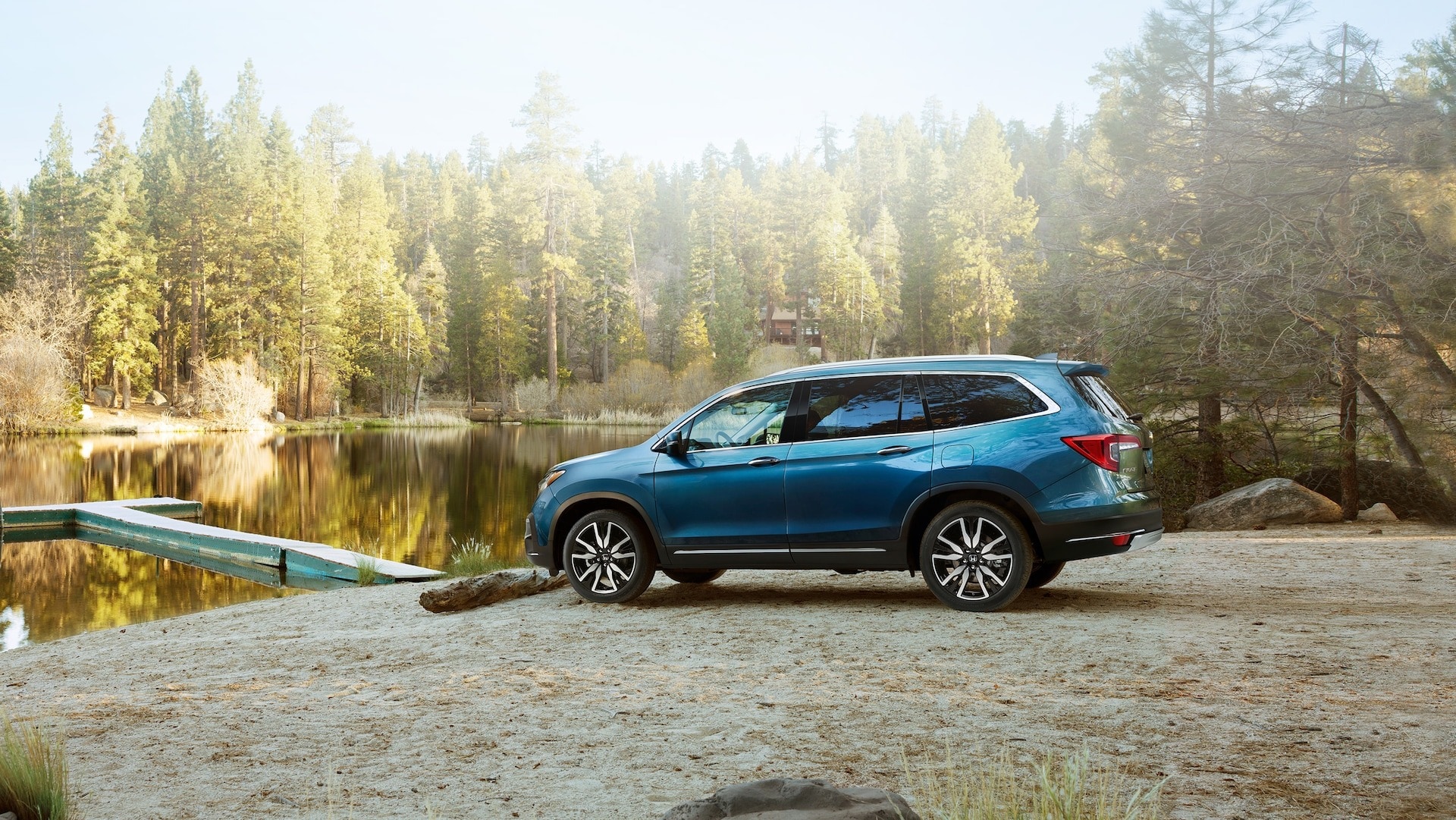 A Blue 2023 Honda Pilot SUV parked next to a lake.jpeg