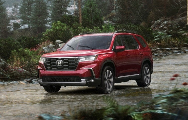 A red 2023 Honda Pilot parked on a dirt road in the wilderness.jpeg
