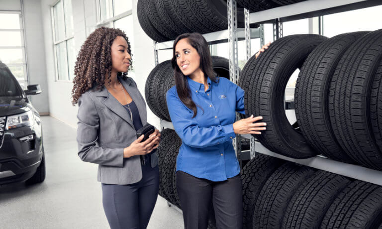 Ford Service Technician with customer looking at tire replacements