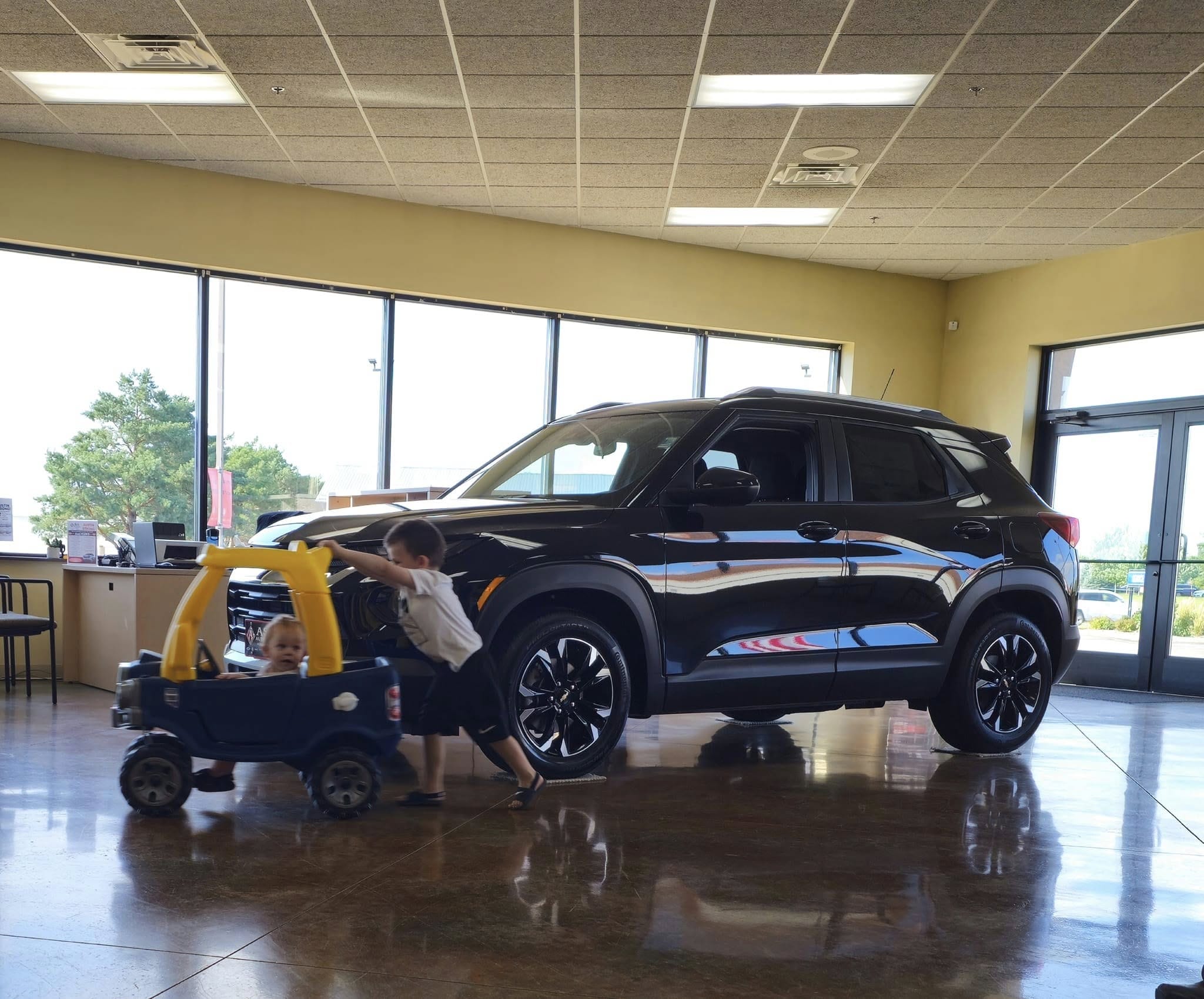 two kids at a gm dealership next to an suv