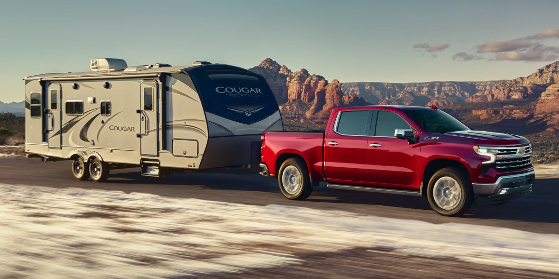 A red silverado 1500 pulling a mobile home on the road.