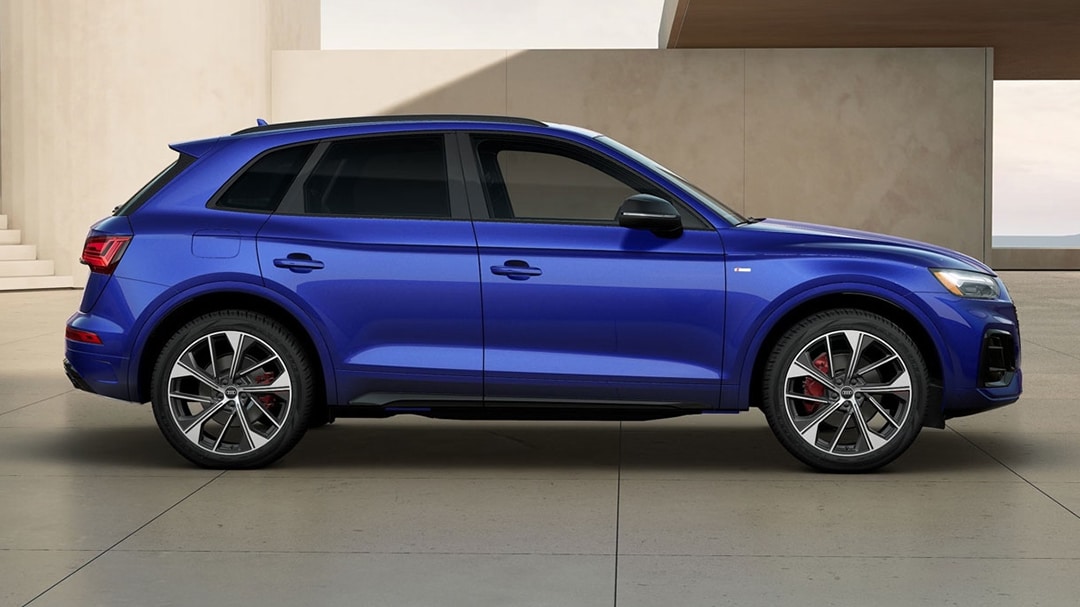 Vue latérale du Audi Q5 2025, garé devant un batîment avec phares allumées