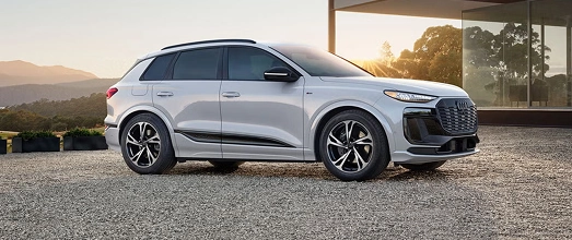 Silver Audi electric SUV parked at sunset, front three-quarter view