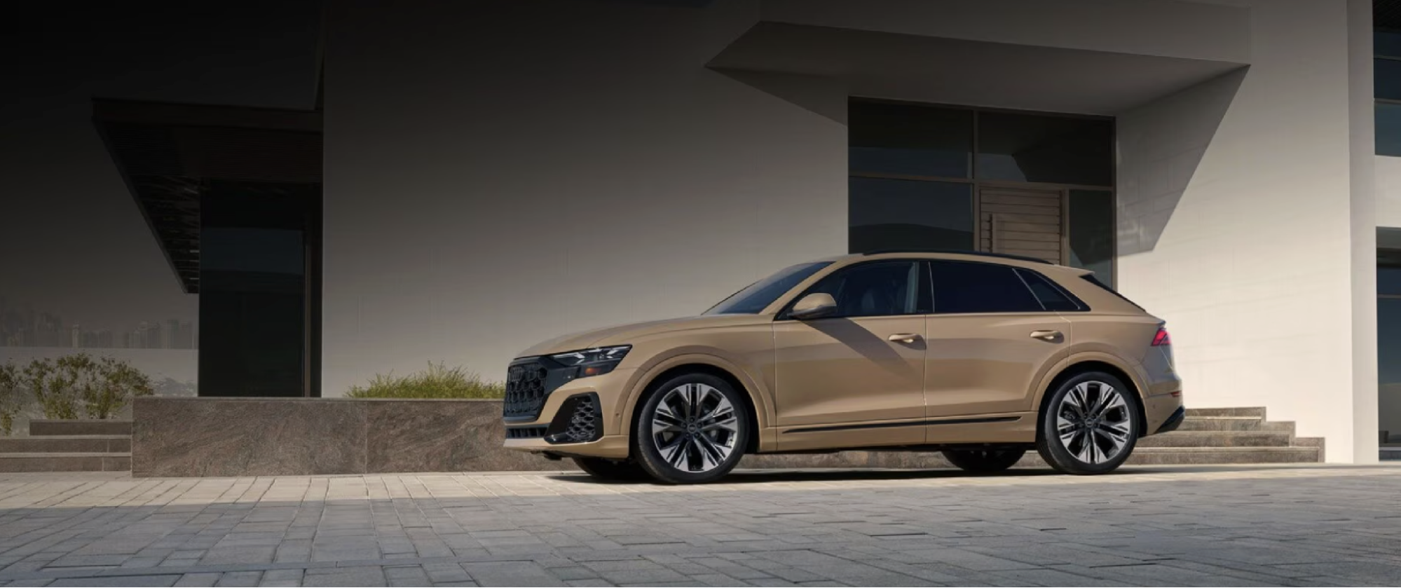 Audi Q8 SUV parked on stone pavers in front of a modern building