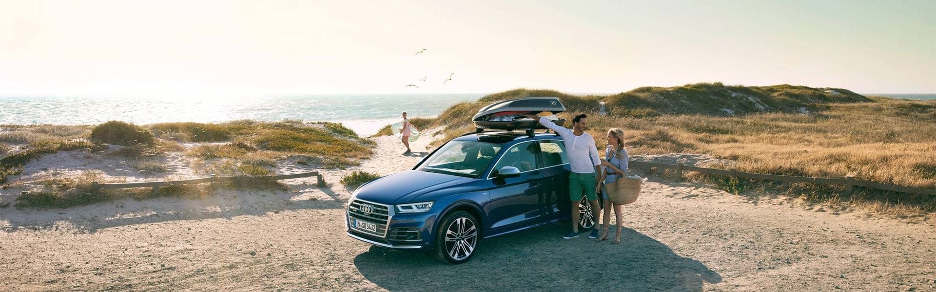 Une famille qui arrive à la plage avec leur voiture Audi.