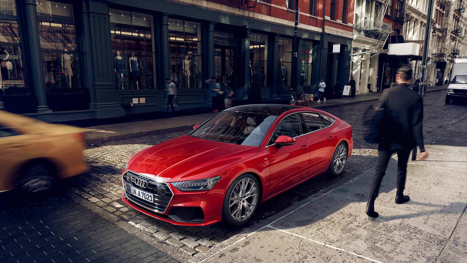 red Audi A7, parked on a cobblestone street with someone walking by the driver's side