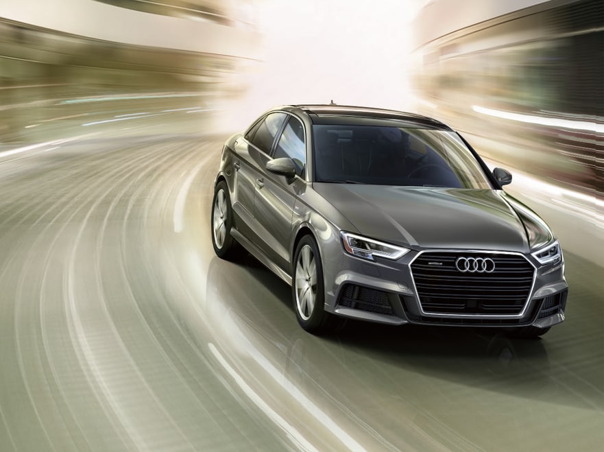 used dark gray Audi A3 sedan with blurred driving background