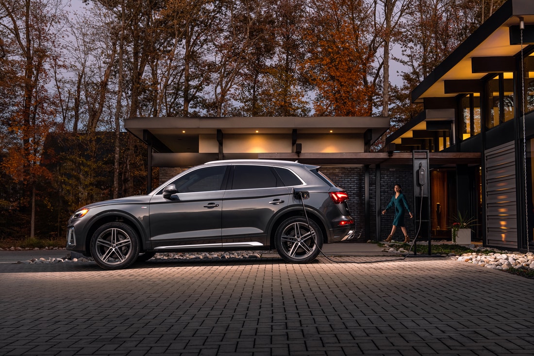 dark gray Audi Q5 e hybrid SUV parked at a charging station in front of a modern home
