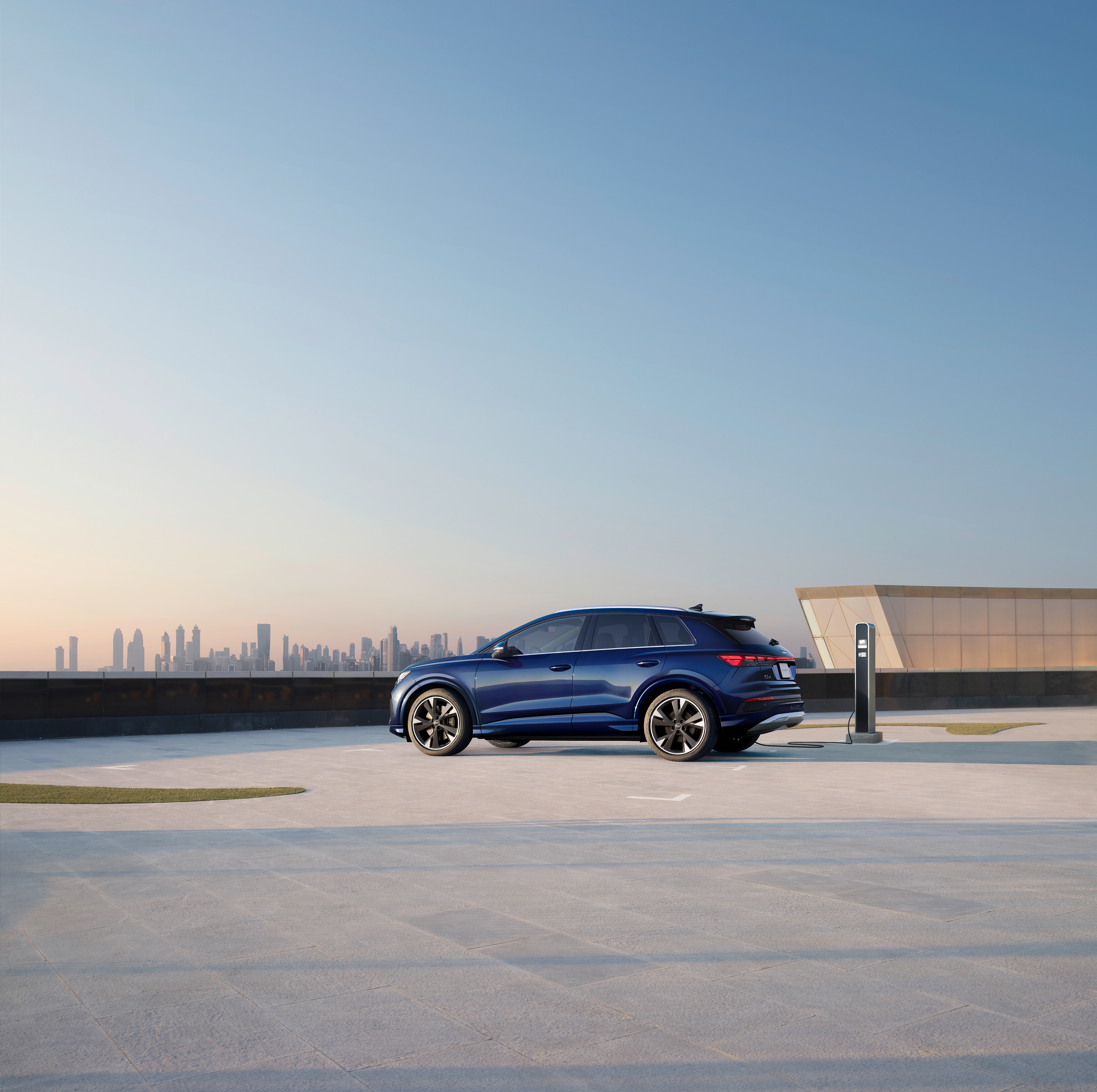 blue Audi Q4 e-tron electric SUV parked at a rooftop charging station