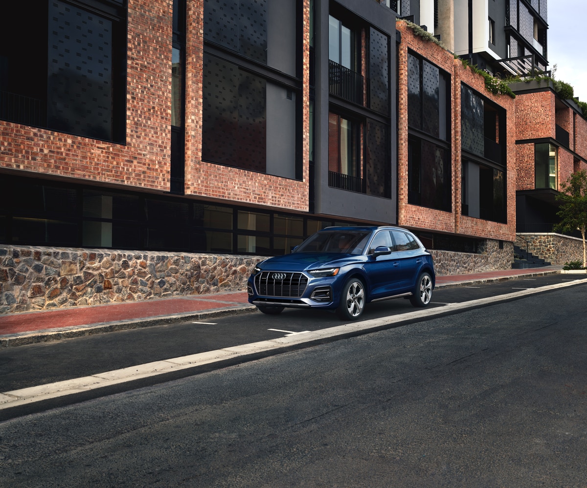 used blue Audi Q5 SUV parked in front of a modern brick building