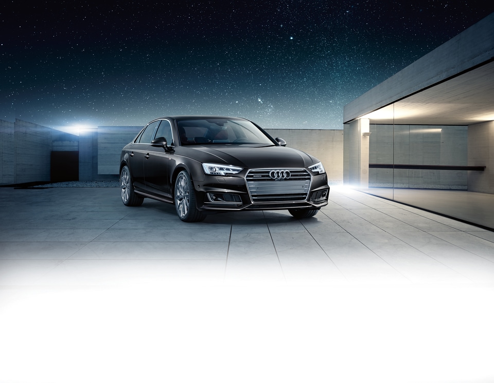 black Audi A4 sedan parked in a modern driveway under stars