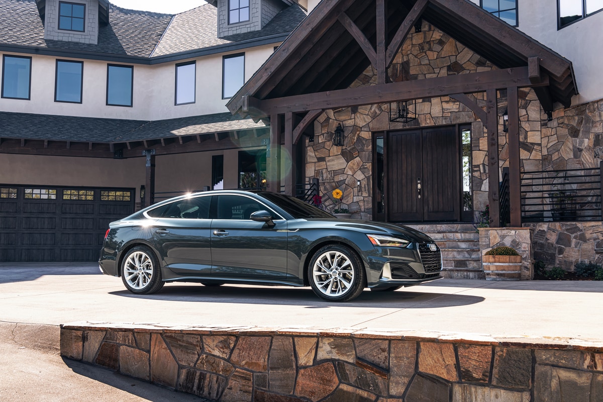 dark green Audi A5 sedan parked in front of a modern lodge