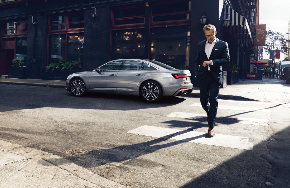 sliver Audi A6 sedan parked with a man in a suit walking away