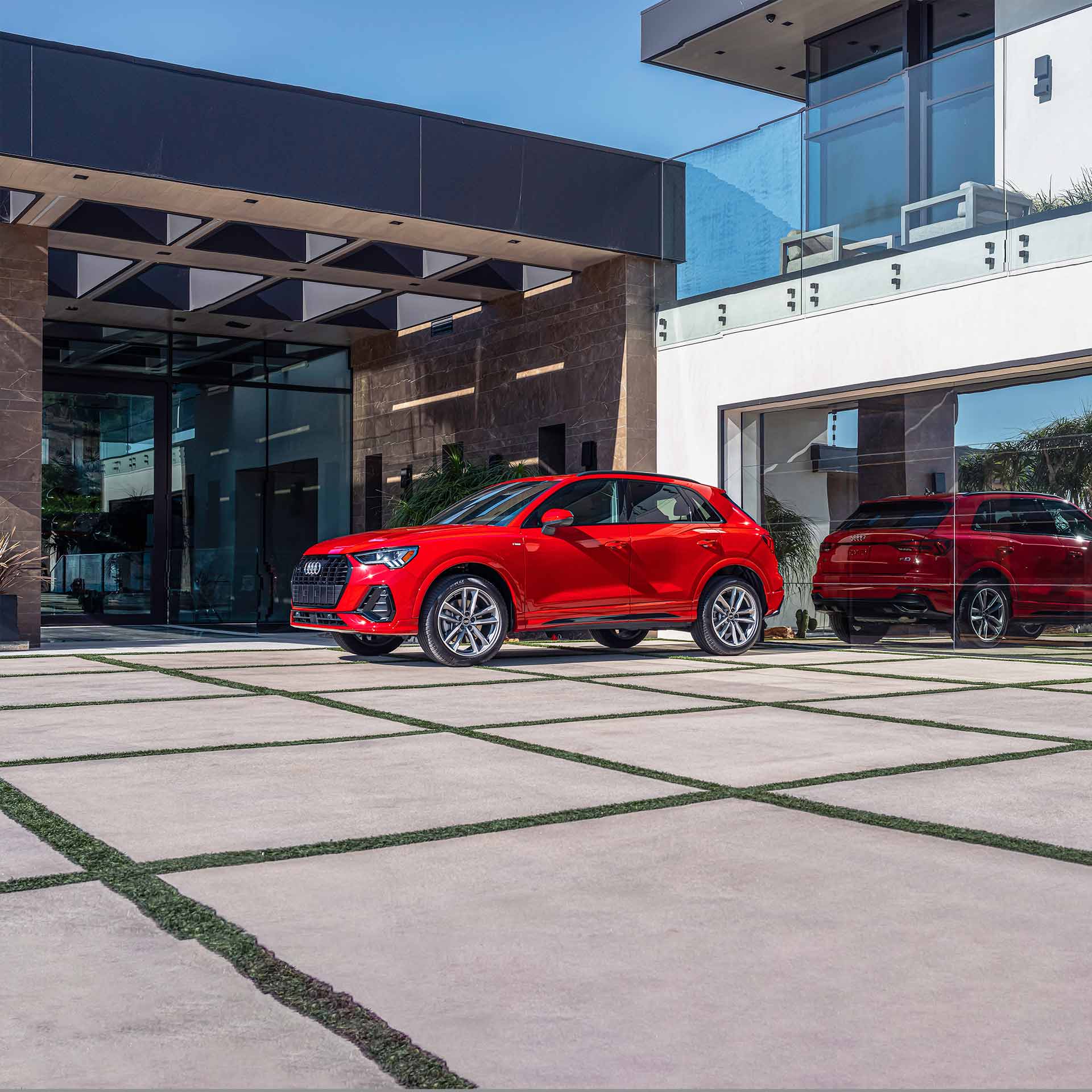 red Audi Q3 parked in front of a modern hotel entrance
