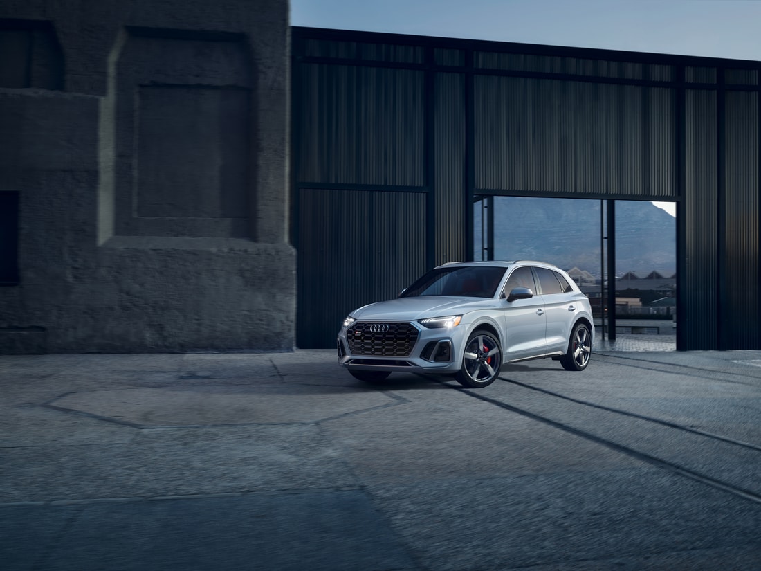 white Audi SQ5 SUV parked in front of a stone grey modern building
