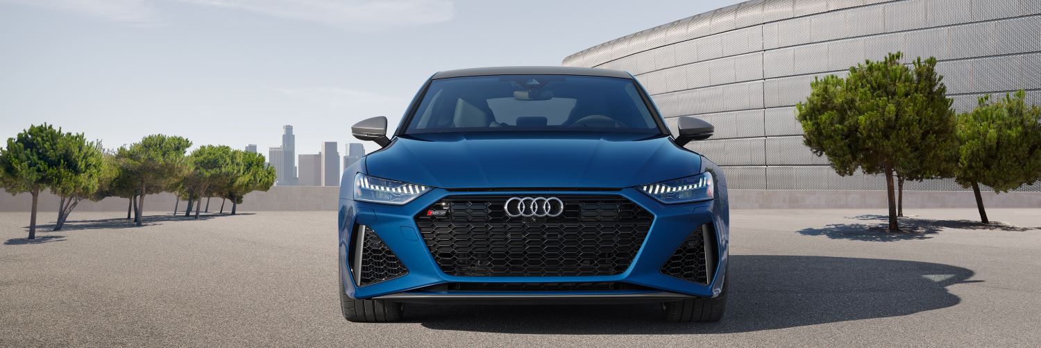 Blue Audi A7 front grille parked near some manicured trees