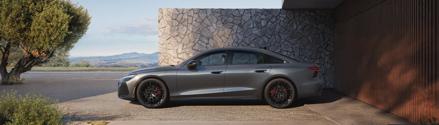 Audi A6 parked next to a gray stone wall