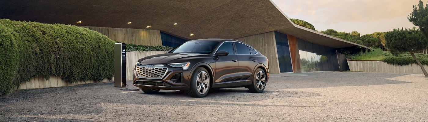 Audi Q8 e-tron parked at a charger by a modern house