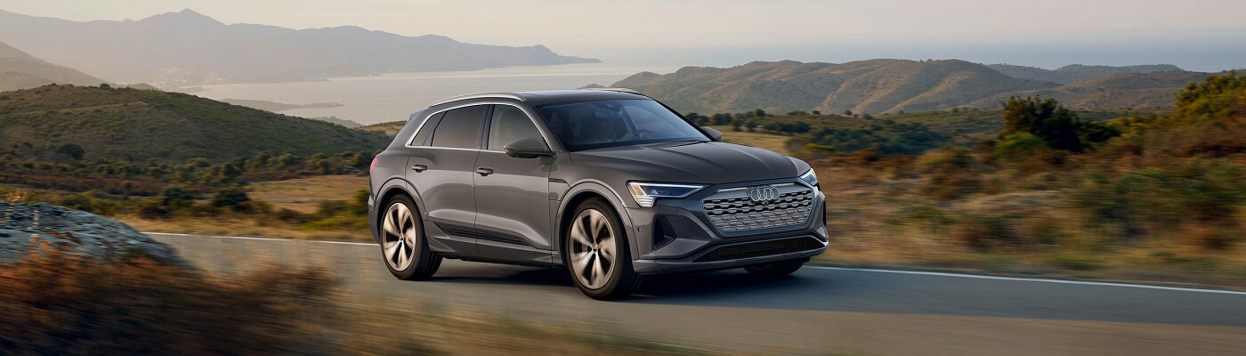 Audi Q8 e-tron Audi Q8 e-tron driving on a road by a lake