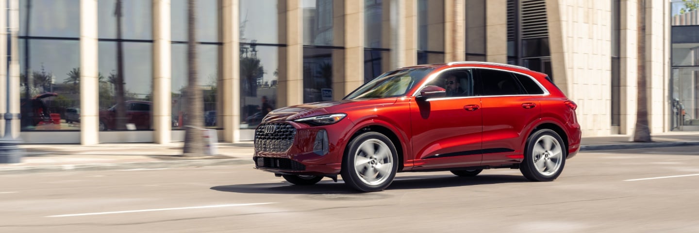 Red Audi Q5 driving down a city street