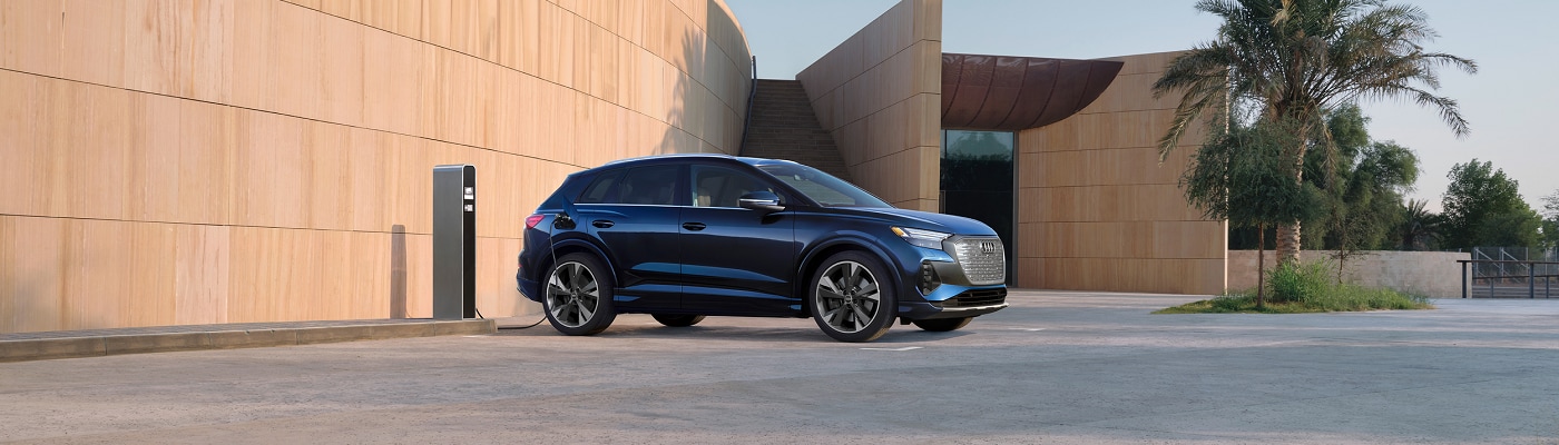 Blue Audi Q4 e-tron charging in front of a modern house