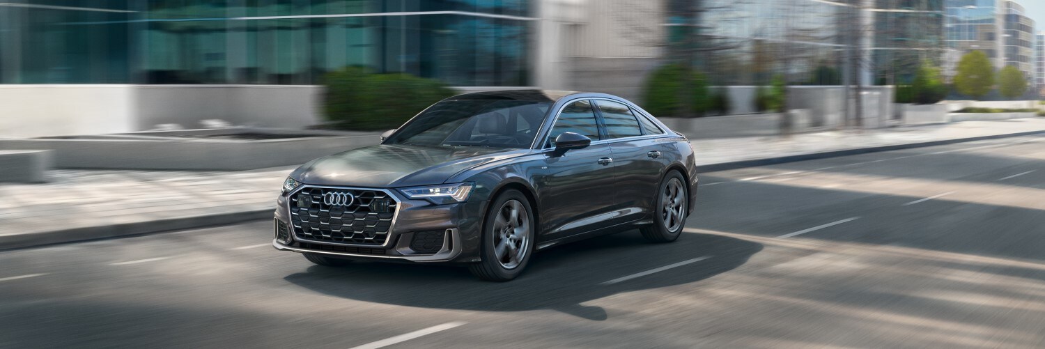 Gray Audi A6 sedan driving down a city street