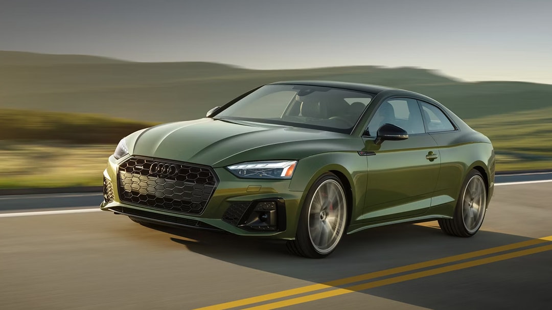 Vue 3/4 avant et latérale de l'Audi A5 Coupé 2025 sur route en pleine puissance