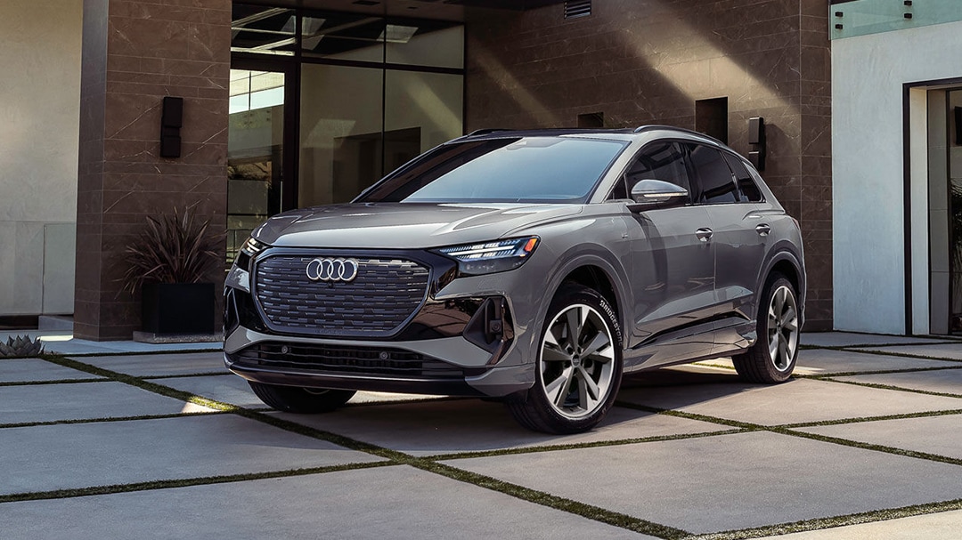 3/4 front and side view of Audi Q4 e-tron parked in front of luxury home