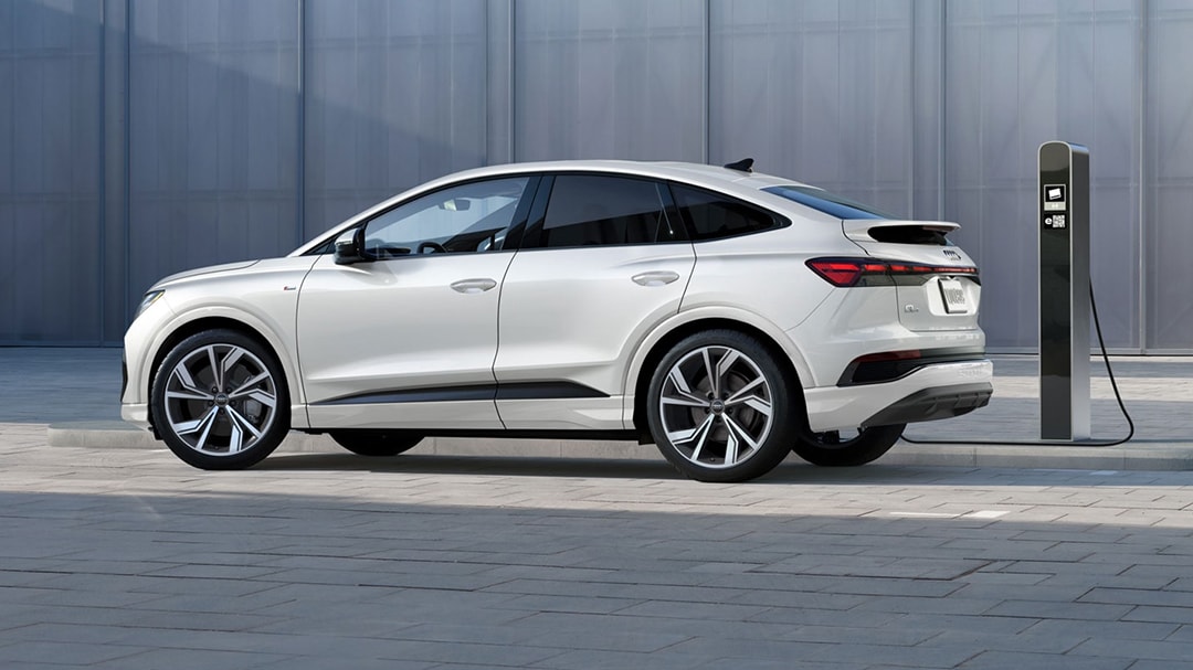 Side view of the Audi Q4 Sportback e-tron 2025 charging with a charging station