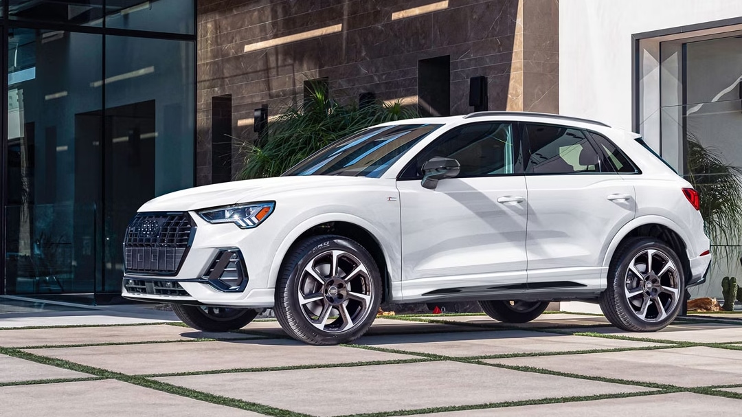 Vue latérale de L'Audi Q3 2025, garé devant bâtiment luxueux et cour pavé