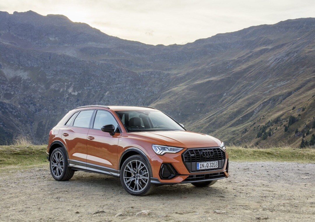 vue 3/4 avant de l'Audi Q3 2019 orangé dans les montagnes