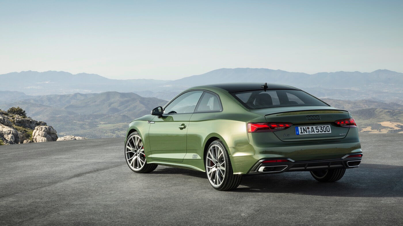 Vue 3/4 arrière de l'Audi A5 coupé 2023 vert District face à des montagnes au loin