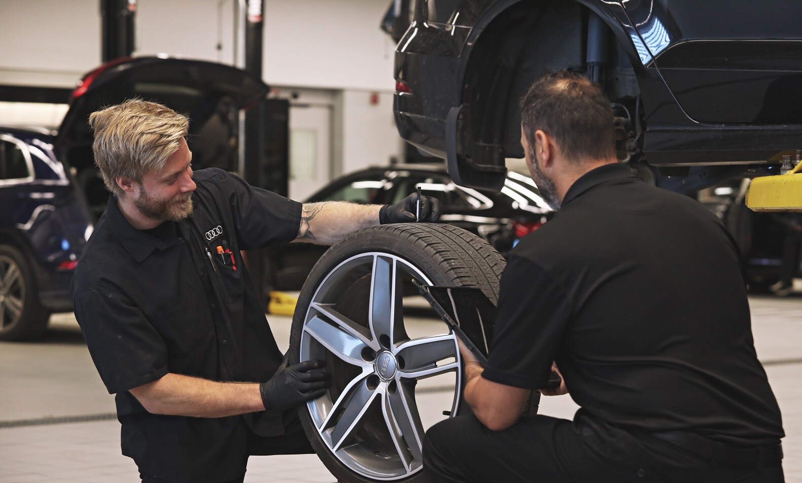 deux personnes inspectant un pneu pour une Audi