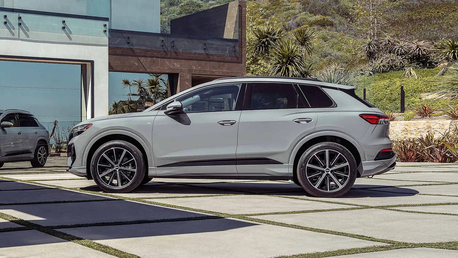 Vue latérale de l’Audi Q4 e-tron 2023 Gris Gravier garé à la maison.