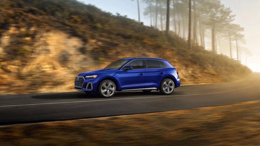 Vue latérale et 1/4 avant de l’Audi Q5 roulant sur une route.