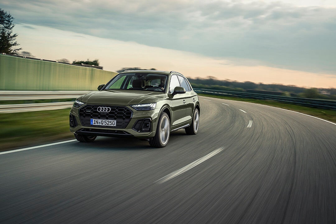 Vue 3/4 avant d'un VUS Audi Q5 version de base vert roulant sur une route