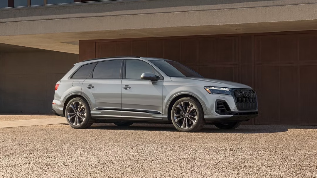 Side view of Audi Q7 2025 parked in front of a wooden wall
