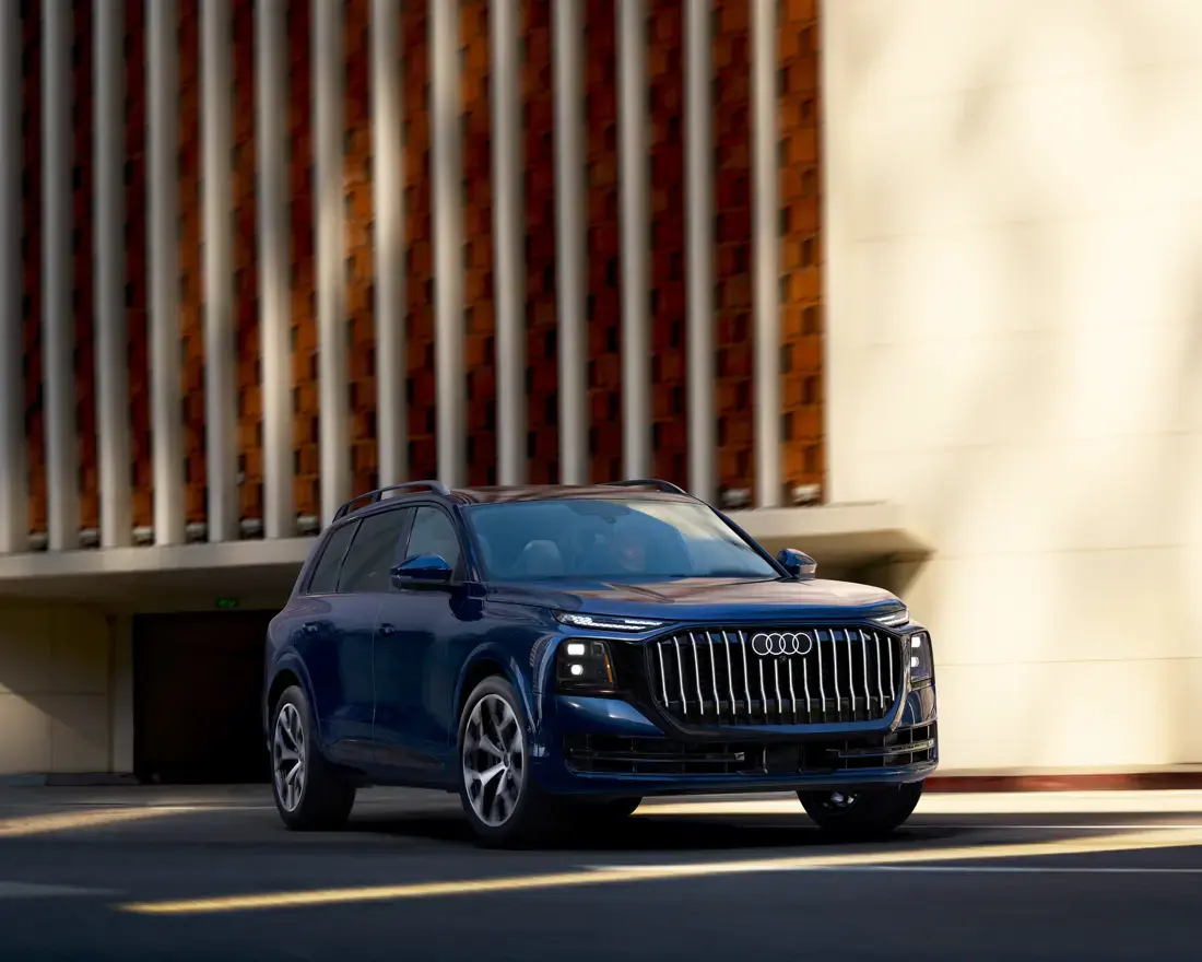 Blue 2027 Audi Q9 driving down a city street
