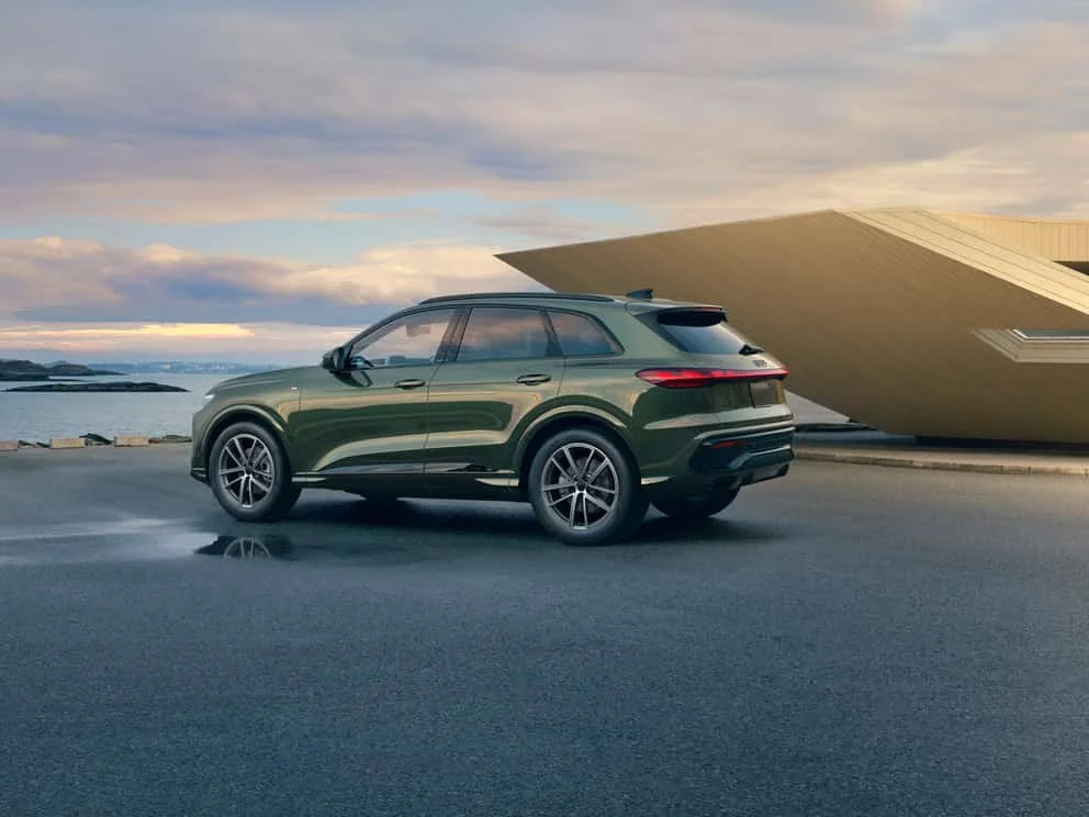2026 Audi Q5 rear three-quarter view beside an angular waterfront pavilion